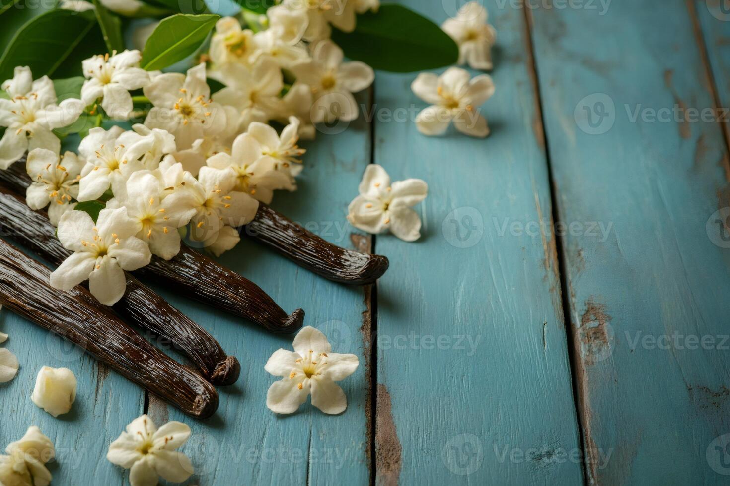 Vanilla pods and flowers resting on rustic blue table photo