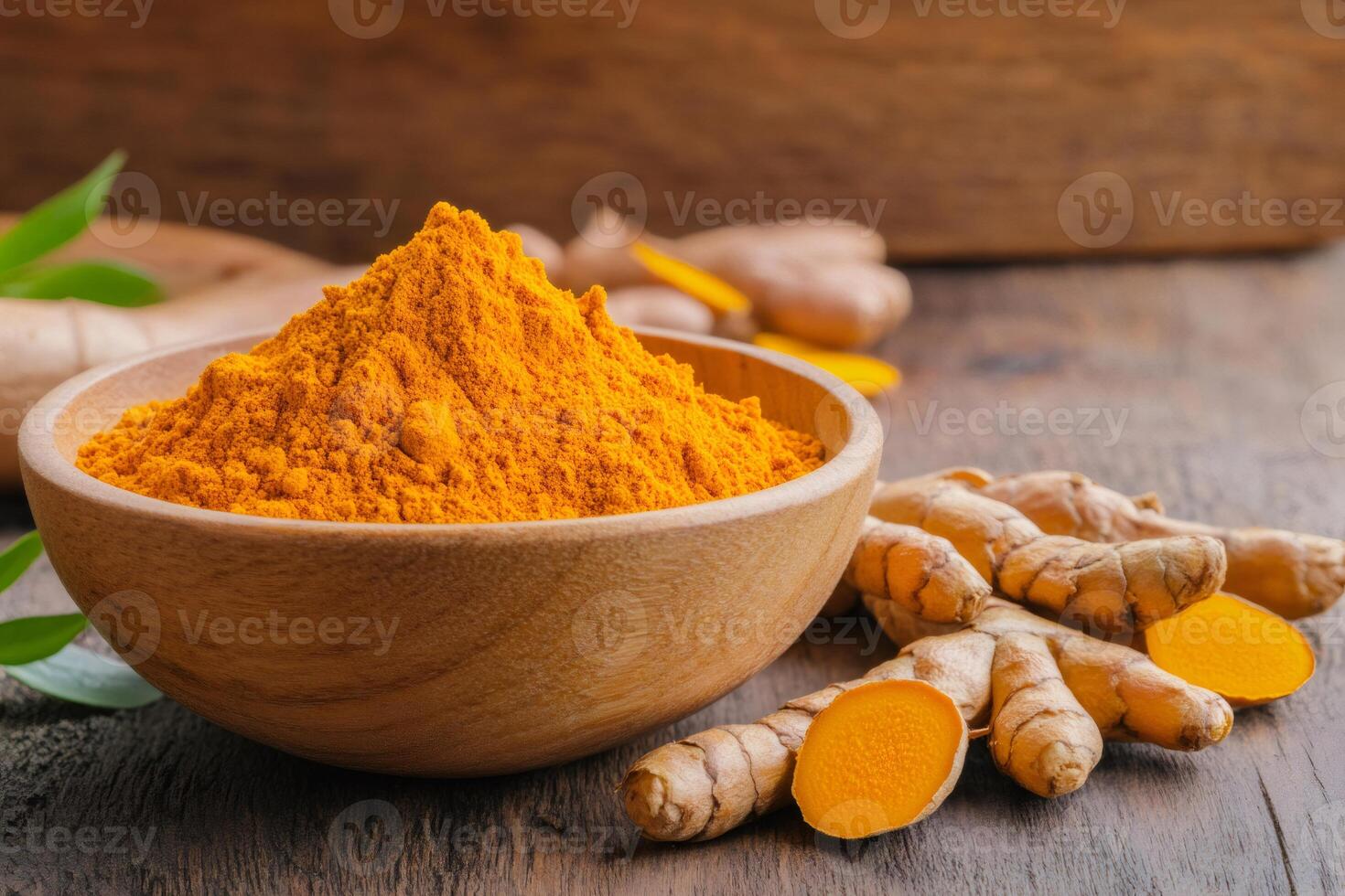 Turmeric powder in wooden bowl and fresh turmeric root on rustic table photo