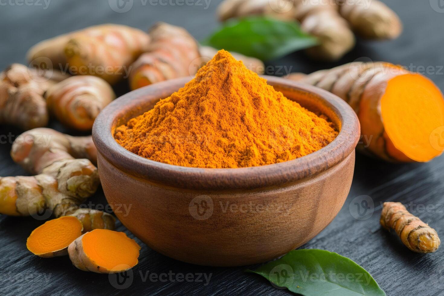 Turmeric powder in wooden bowl with turmeric roots and green leaves photo