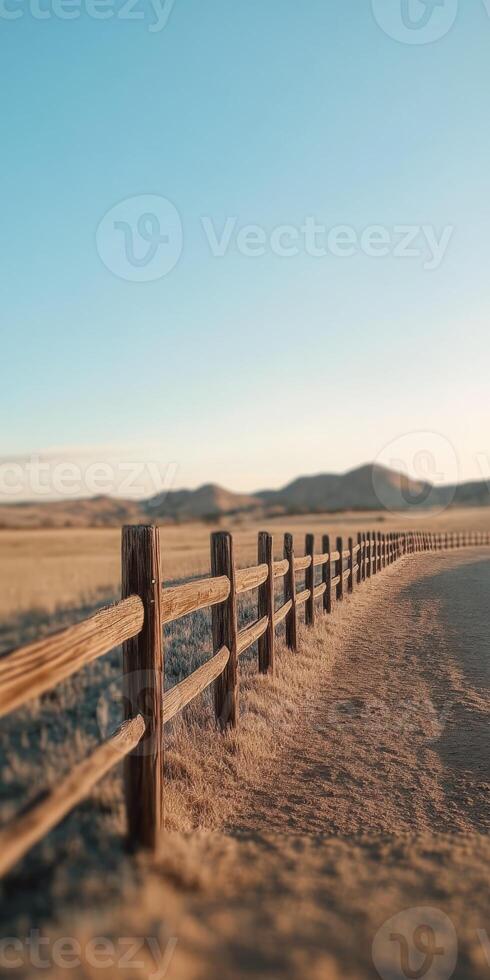 Beautiful dirt road with wooden fence under clear blue sky in rural landscape photo