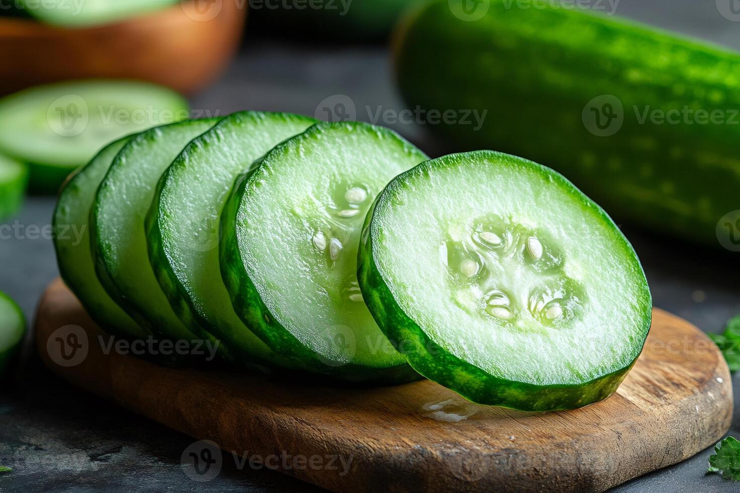 Fresh cucumber slices resting on wooden cutting board photo