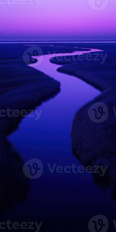 A river flows through a marsh at dusk photo