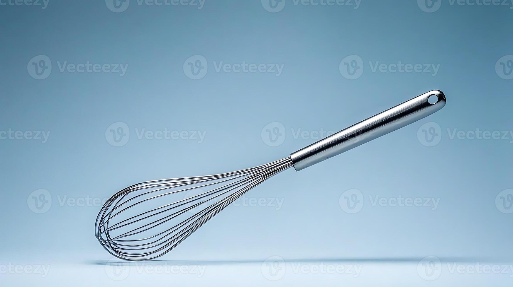 Stainless steel whisk floating against a soft blue background, ideal for culinary use and kitchen decor photo