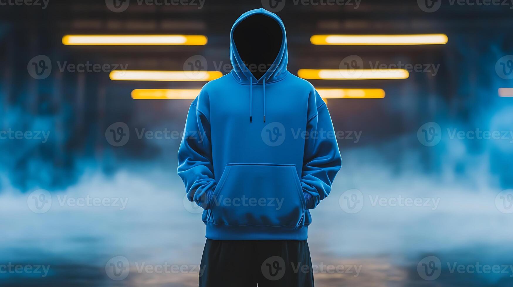 Mysterious figure in a blue hoodie stands in a foggy urban environment with glowing lights photo
