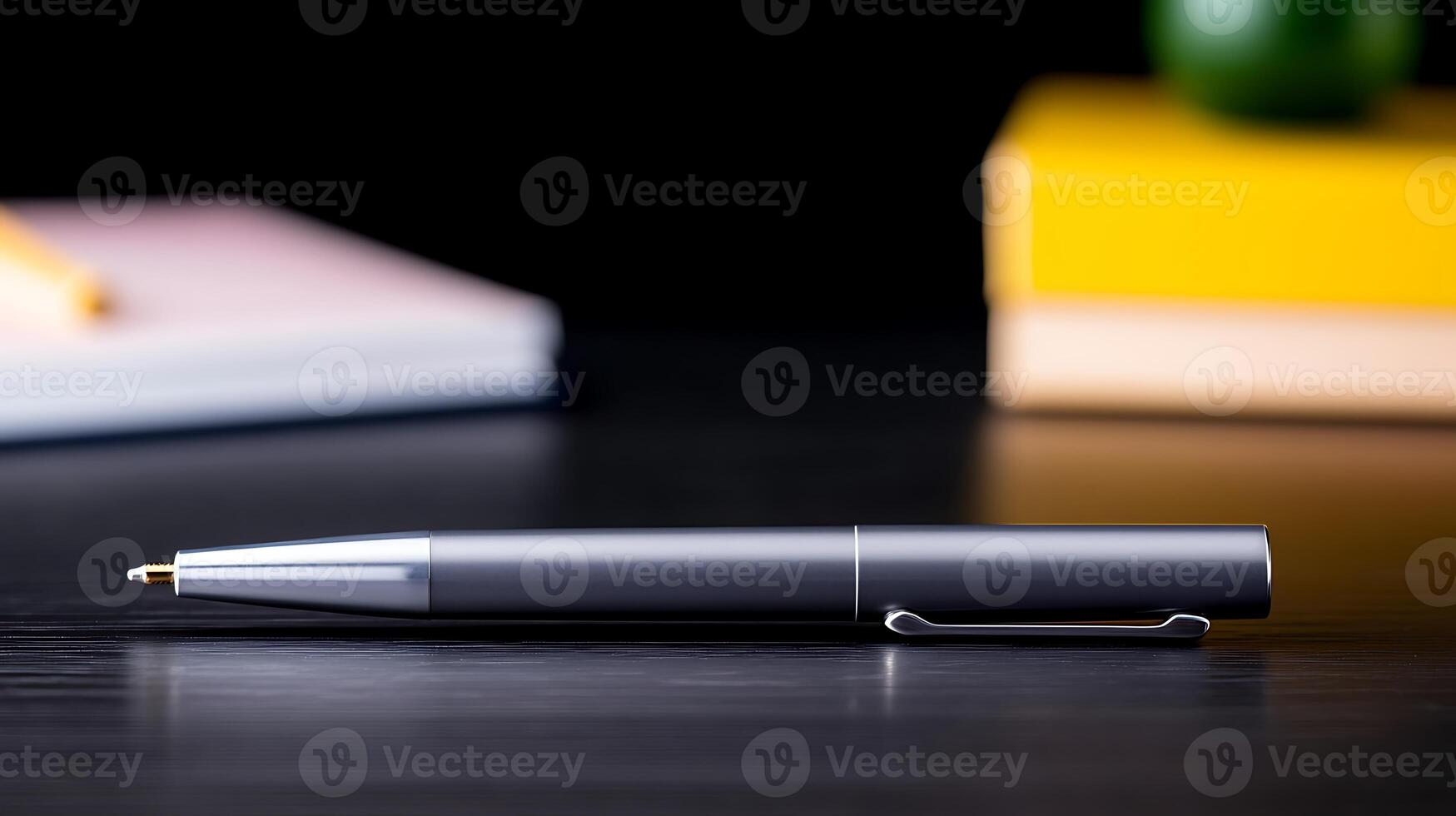 Sleek silver pen resting on a dark wooden table with colorful notebooks in the background photo