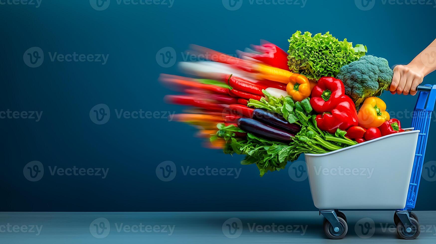 A dynamic shot of a hand pushing a shopping cart filled with vibrant vegetables against a blue backdrop photo