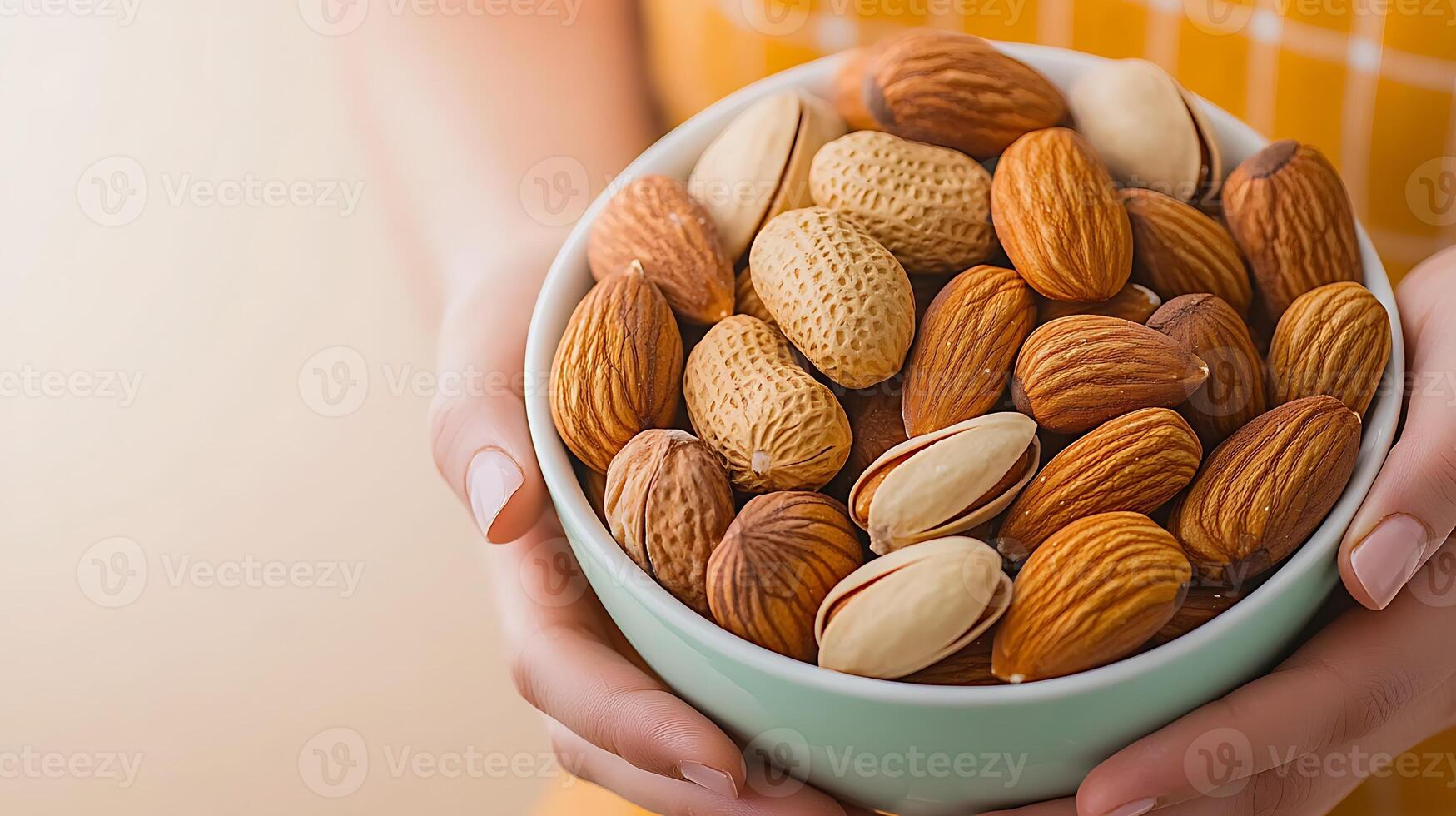 A person holding a bowl of assorted nuts, showcasing a warm kitchen background with soft lighting photo