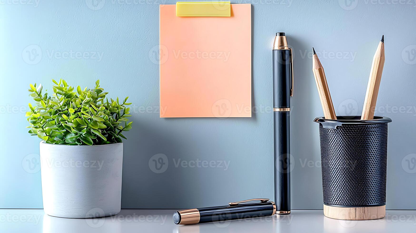 A neatly arranged workspace featuring stationery, a plant, and a blank sticky note for reminders photo