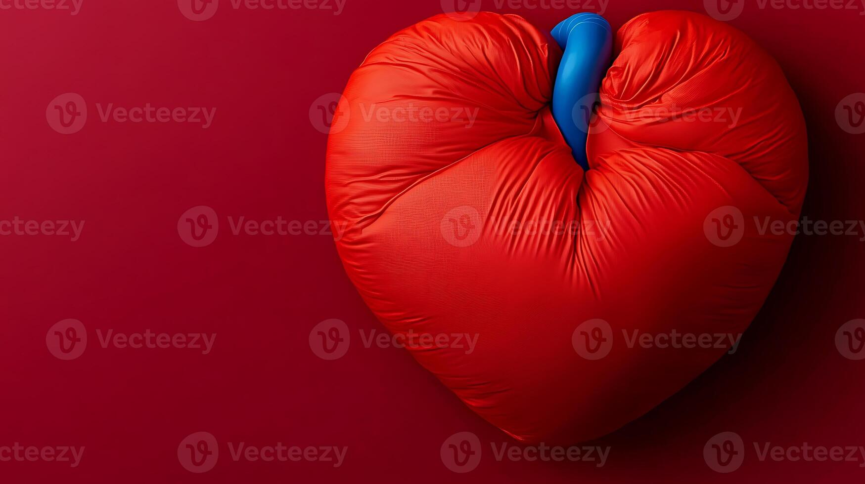 A vibrant red heart-shaped cushion with a blue accent against a solid red background photo