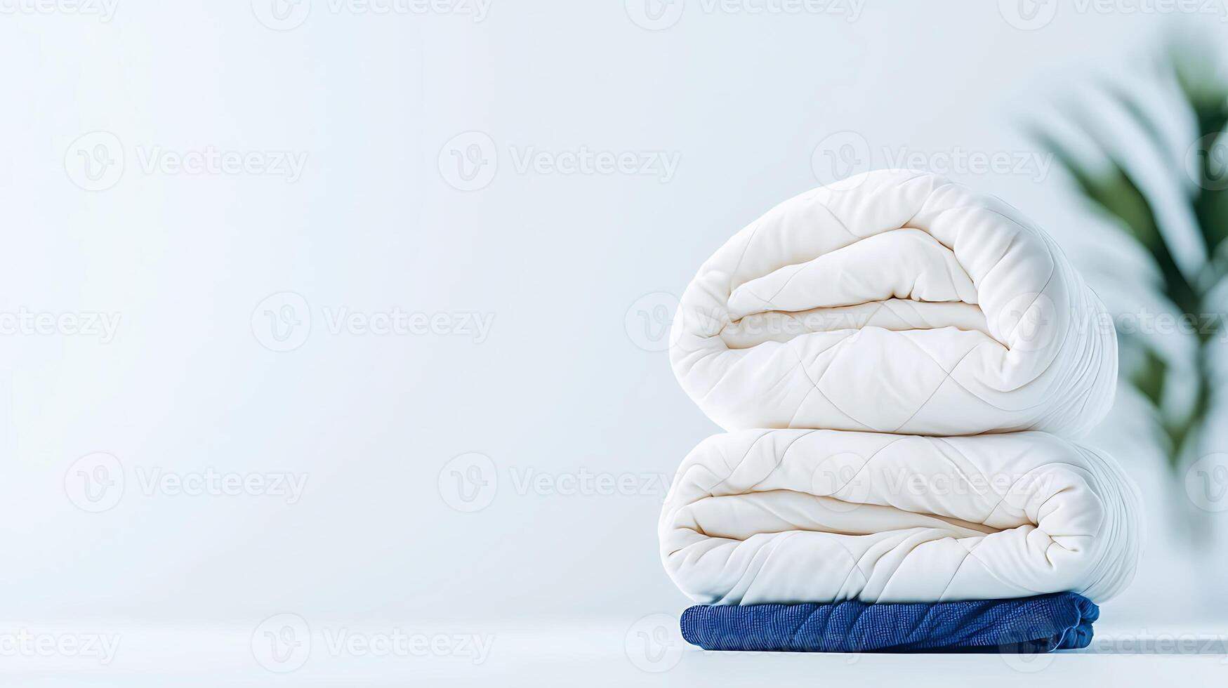 Soft, neatly folded blankets in a serene, minimalistic setting with greenery in the background photo