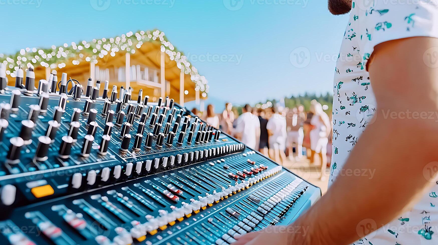 Sound engineer operating a mixing console at a lively outdoor music festival with attendees photo