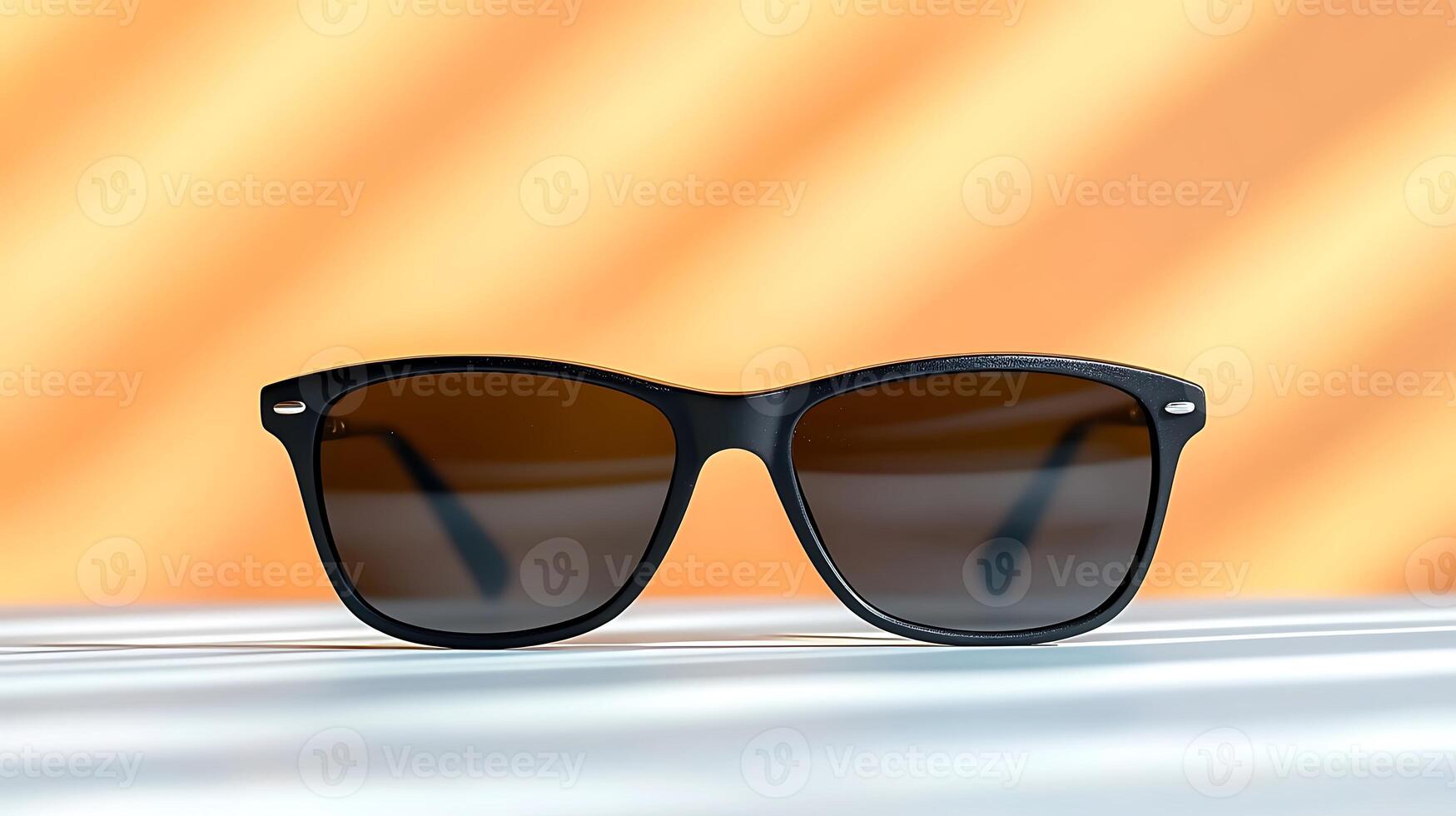 Stylish black sunglasses resting on a surface with soft shadows and a warm orange background photo