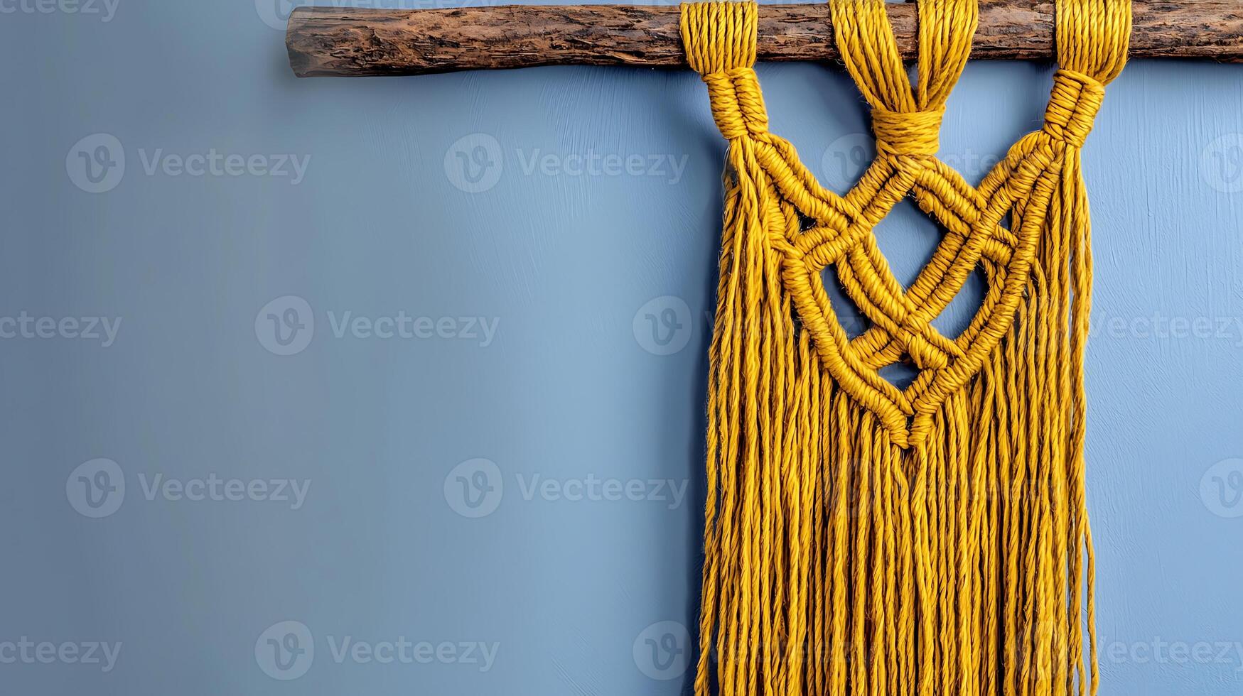 Vibrant yellow macram wall hanging elegantly displayed on a rustic wooden rod against a soft blue backdrop photo