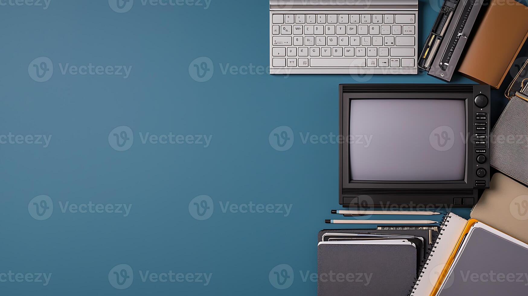 Vintage workspace setup featuring a retro television, keyboard, and stationery on a blue background photo