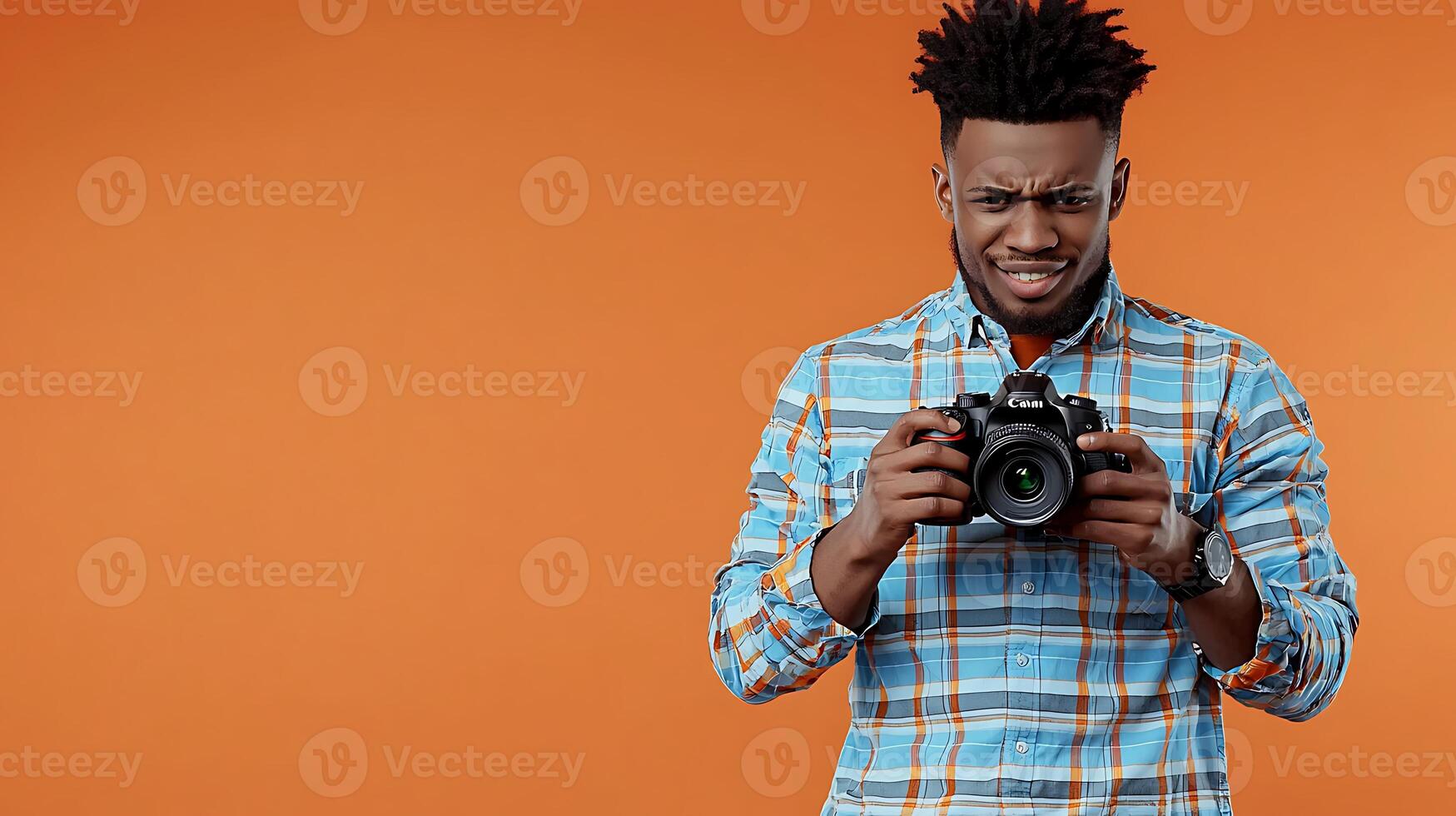 Young man with a camera posing against an orange background, showcasing photography skills photo