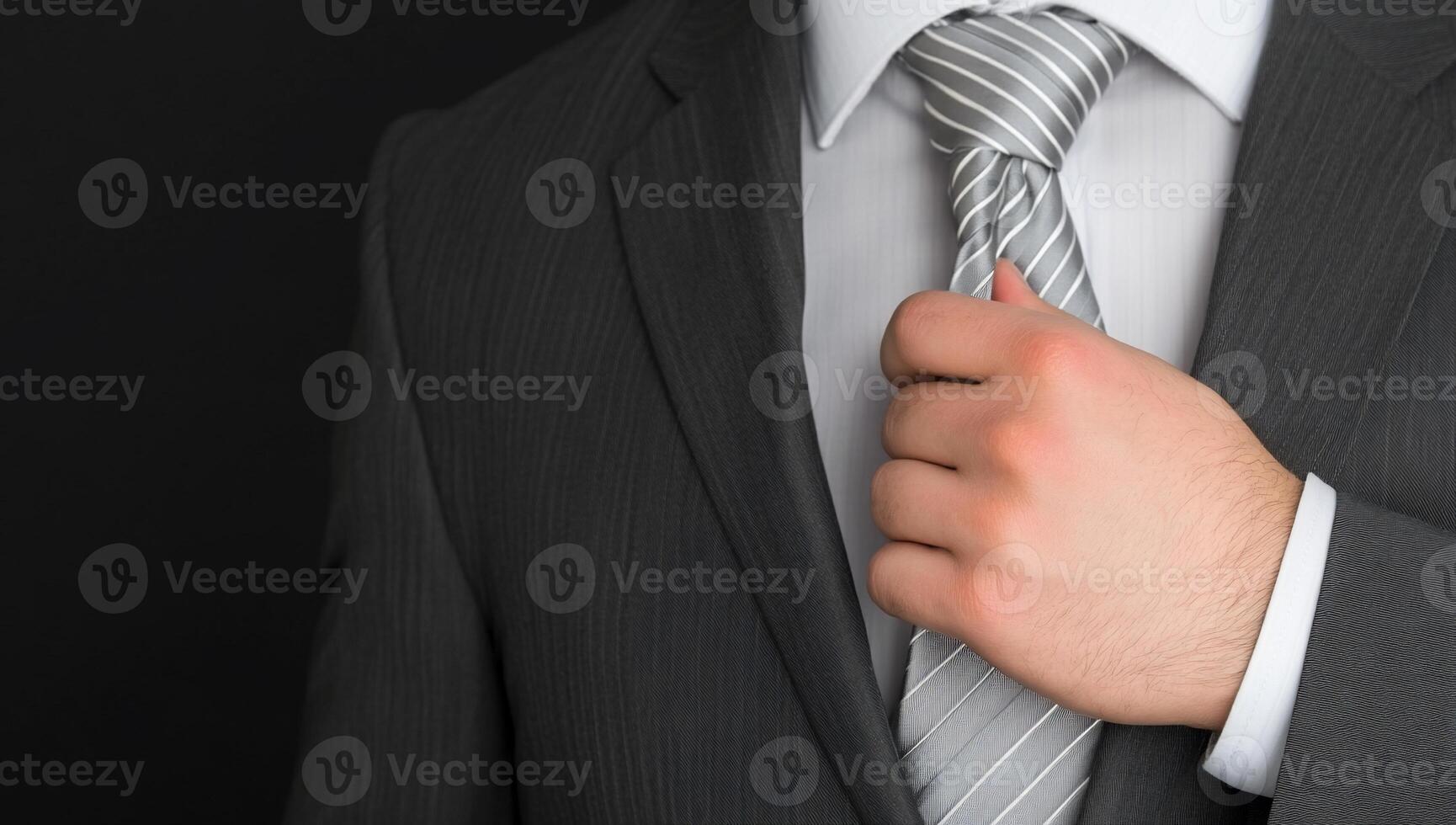 A man in a suit adjusting his tie photo