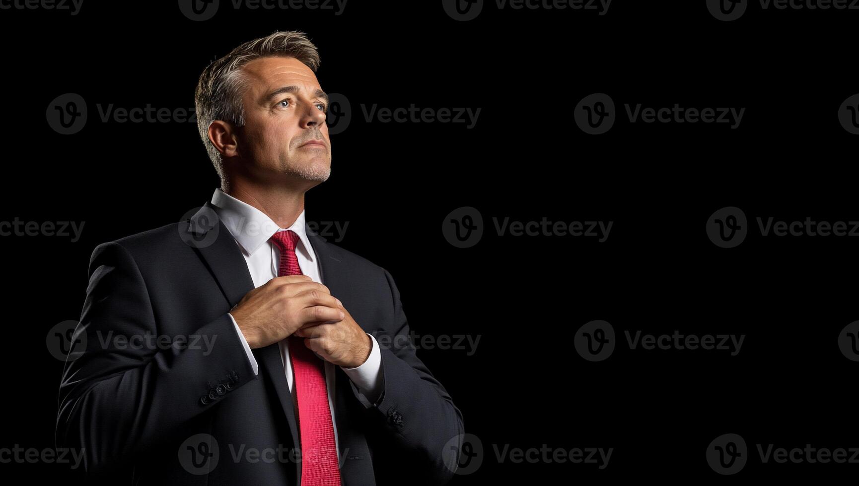 A man in a suit and red tie adjusting his tie photo