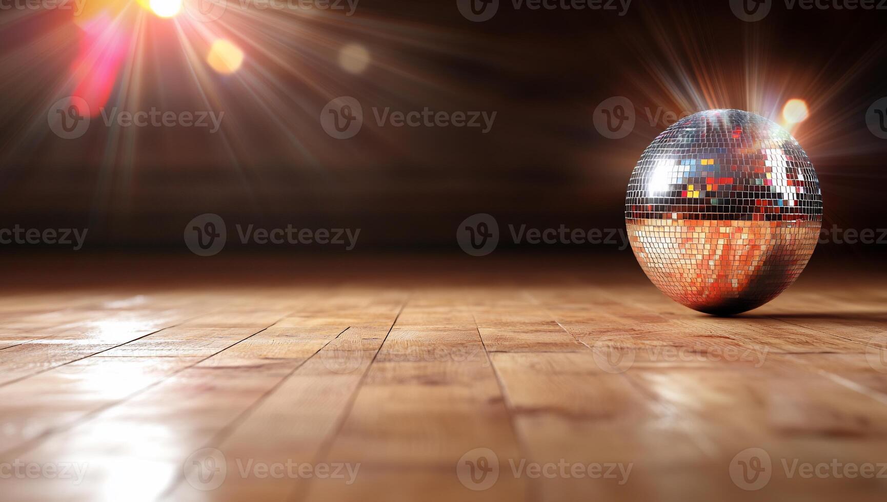 A reflective disco ball on a wooden floor, illuminated by light rays. photo