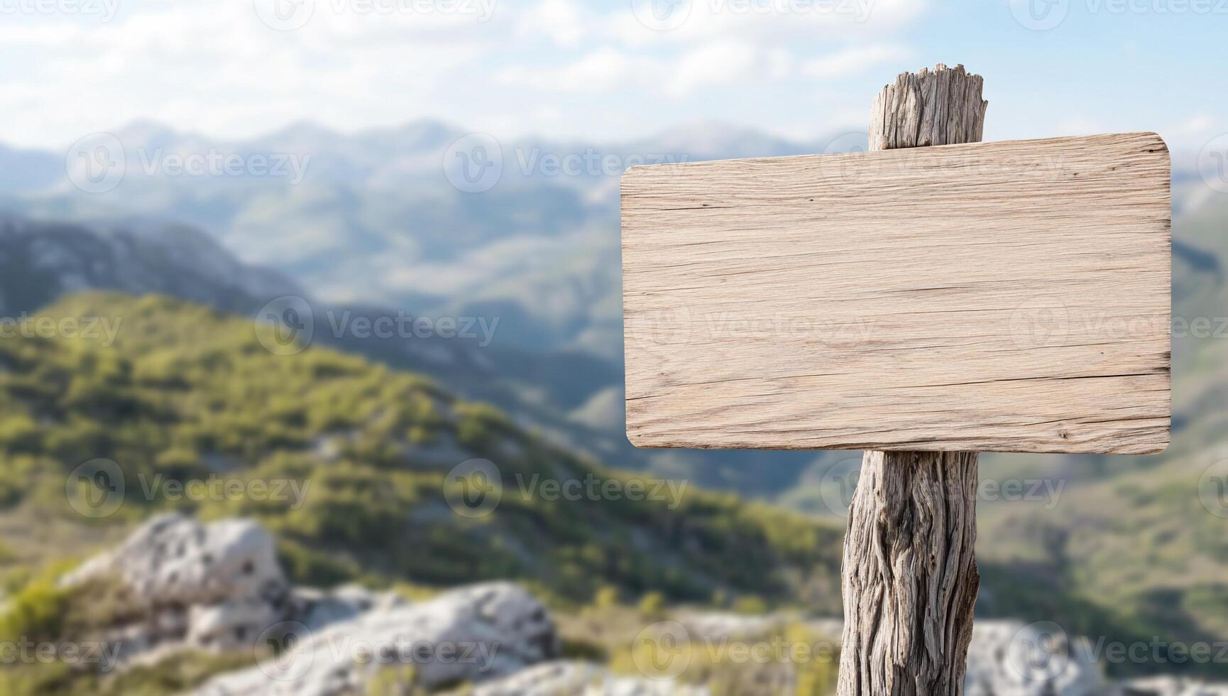 A wooden sign on a wooden post in front of a mountain range photo