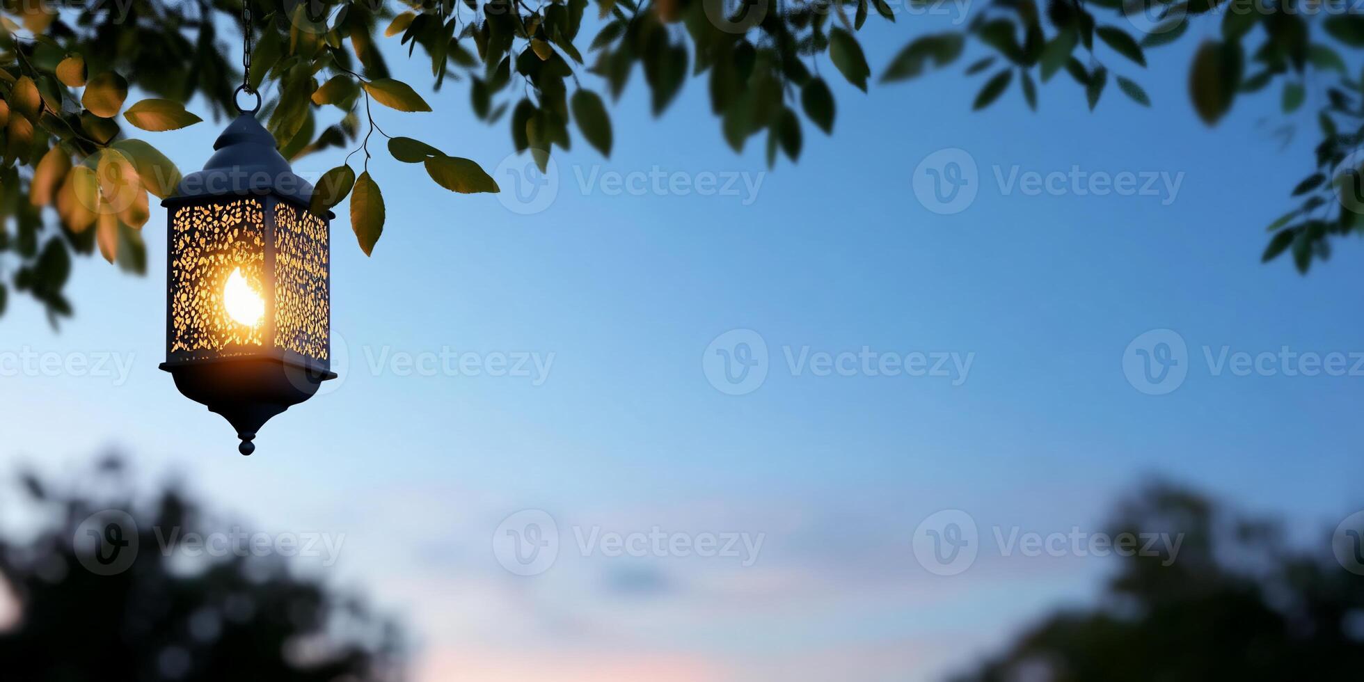 A decorative lantern hangs amid leaves at twilight, casting a warm glow. photo