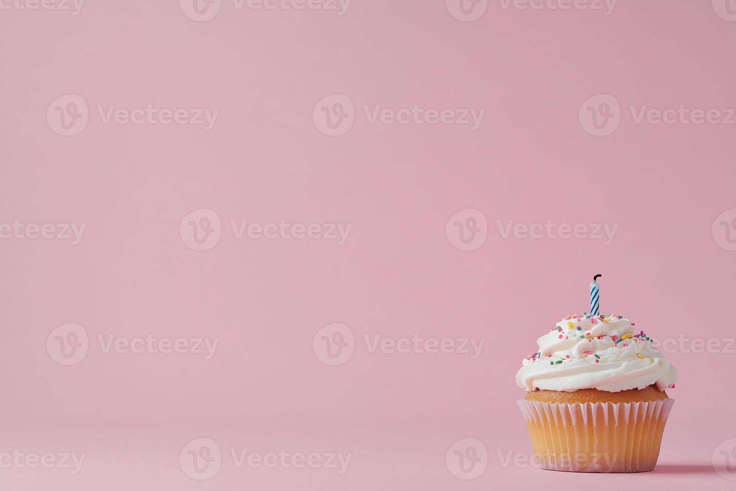 A decorated cupcake with a candle against a pink background. photo