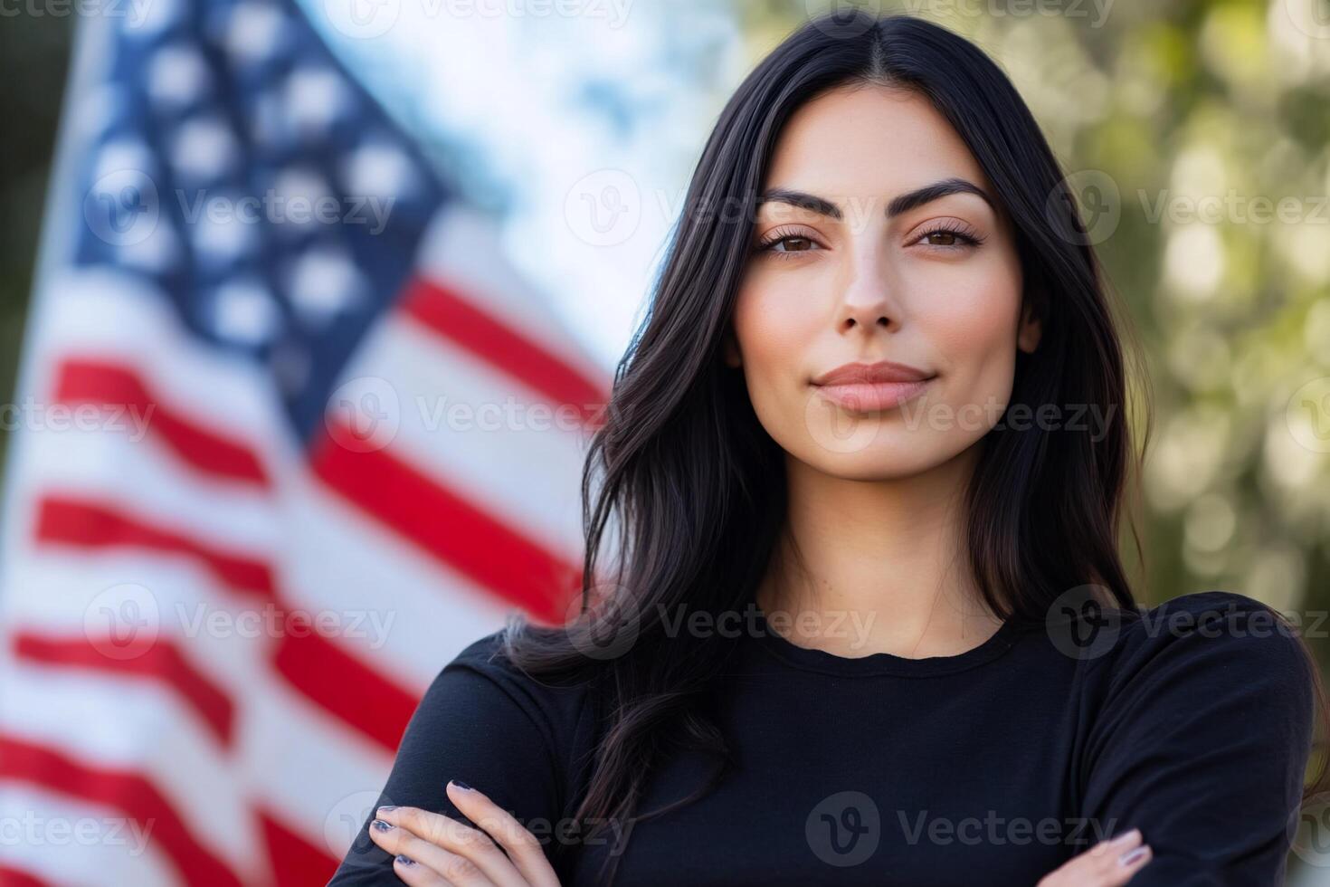 A confident woman stands with arms crossed in front of an American flag. photo