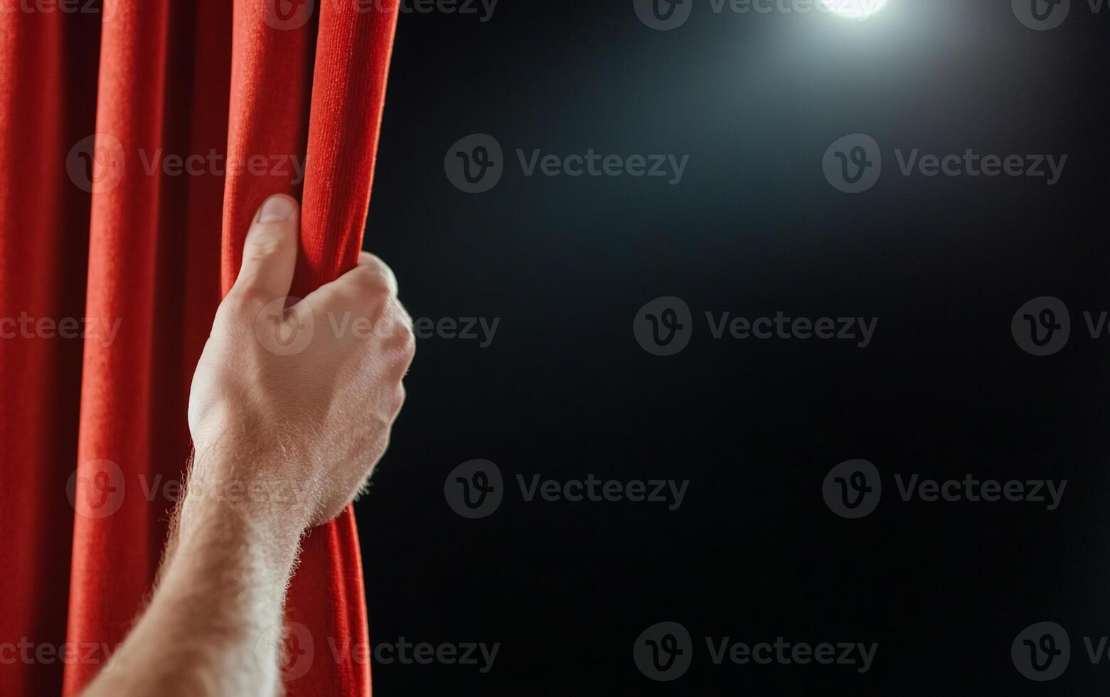 A person's hand reaching out to open a red curtain photo