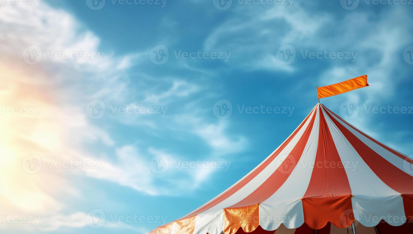 A colorful circus tent under a bright sky with a flag on top. photo