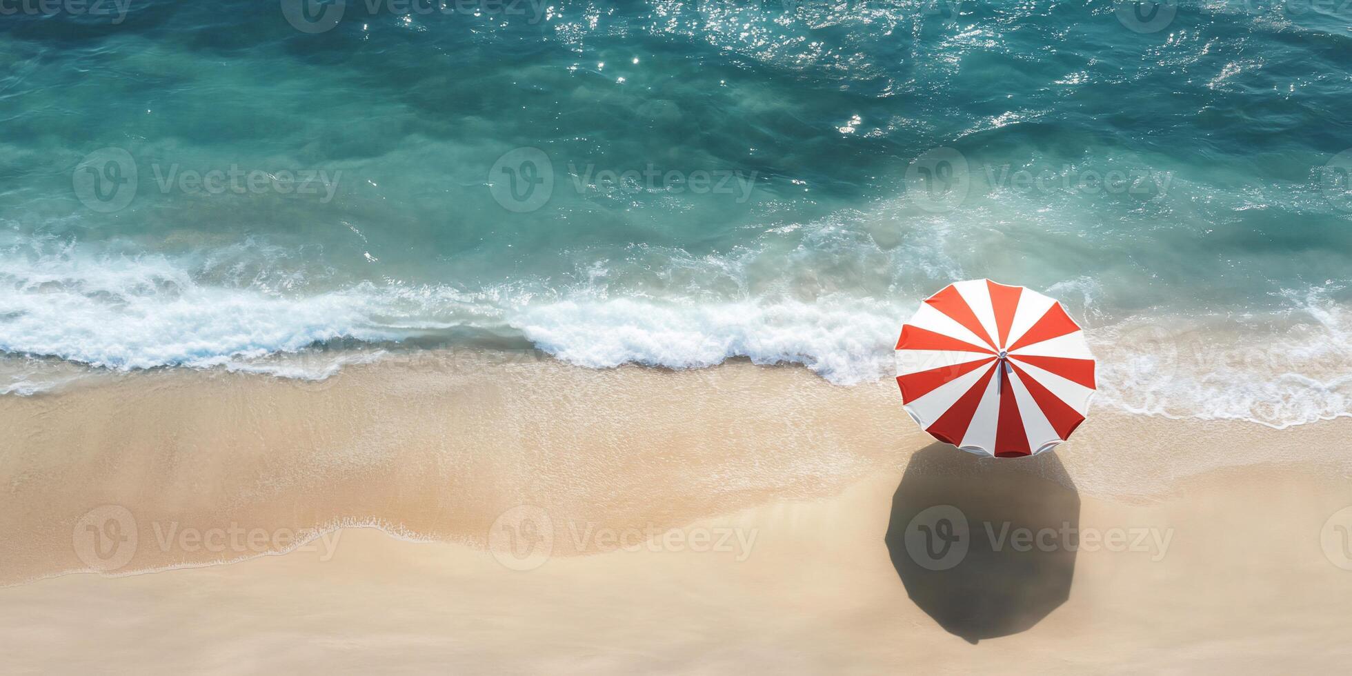 Aerial view of a beach with a red and white umbrella by the shore. photo