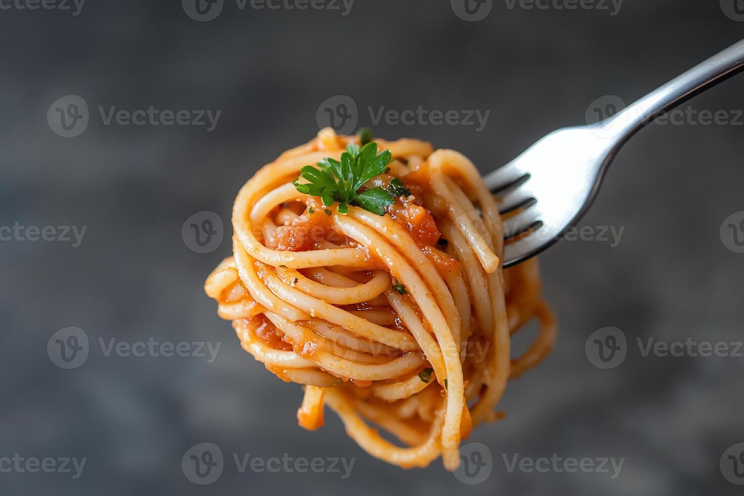 A fork holding a serving of spaghetti with sauce and garnish. photo