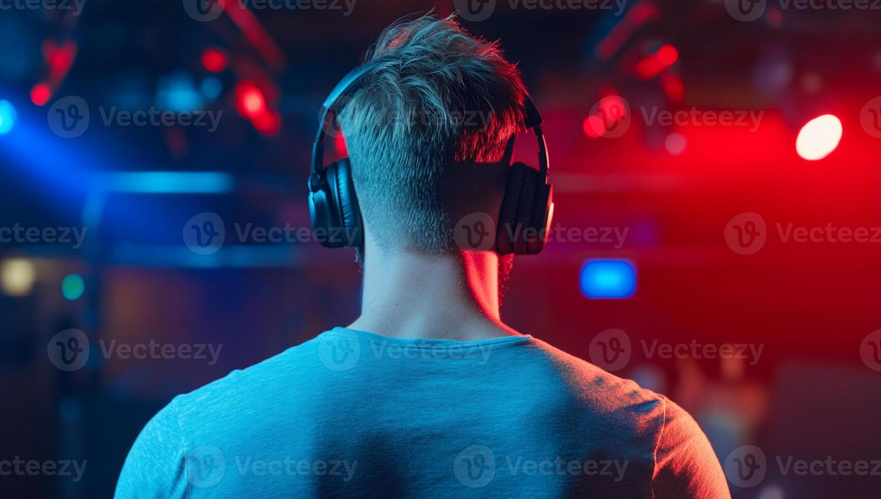 A person with headphones stands in a colorful, illuminated environment. photo