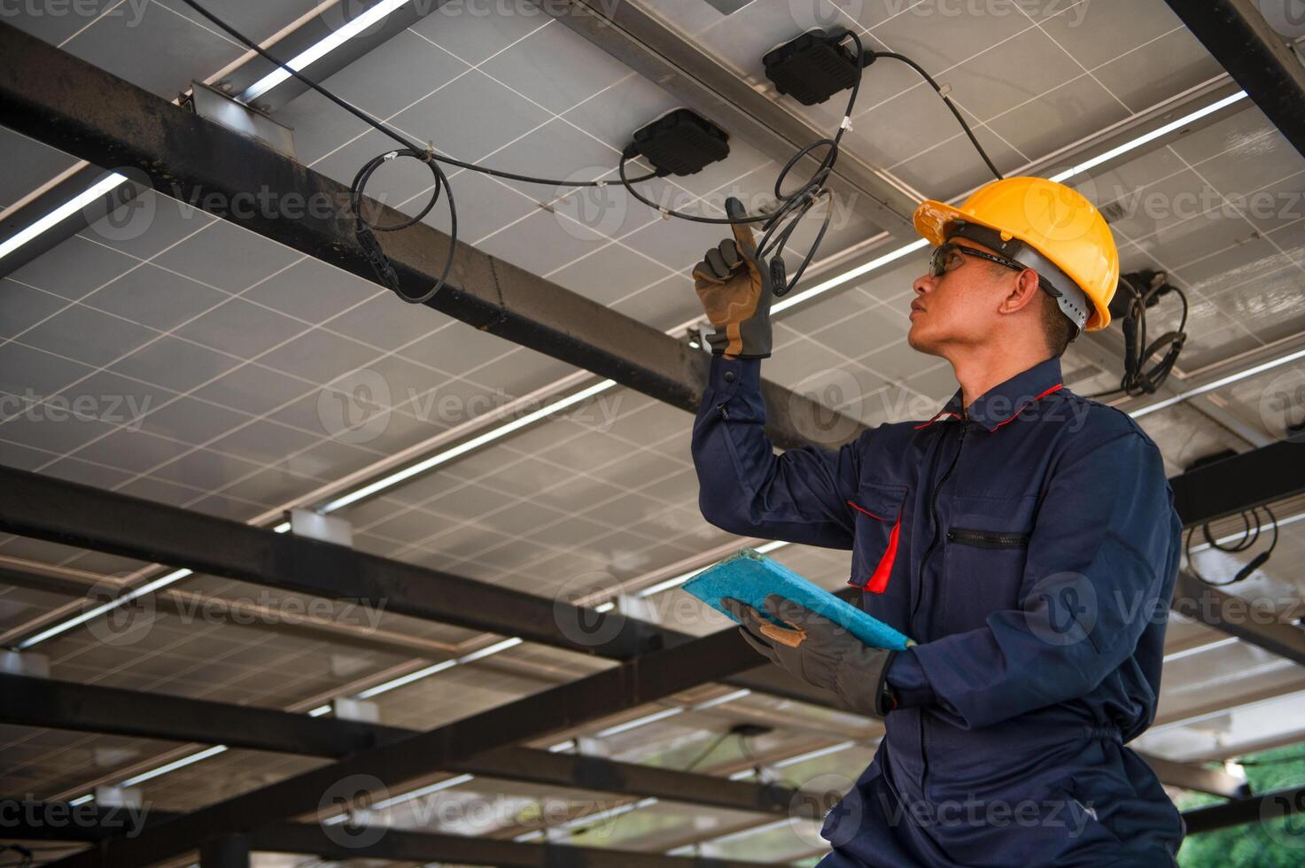 A solar panel engineer monitors the electrical system of his panels using a tablet he holds in his hand photo