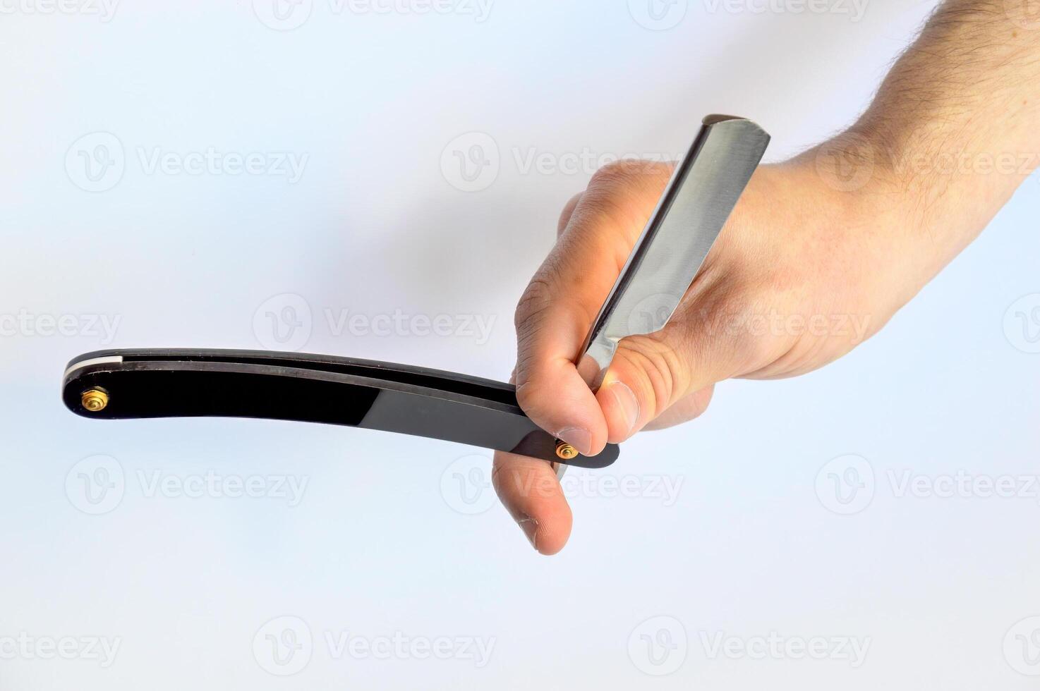 Male hand holding black straight razor isolated on white background photo
