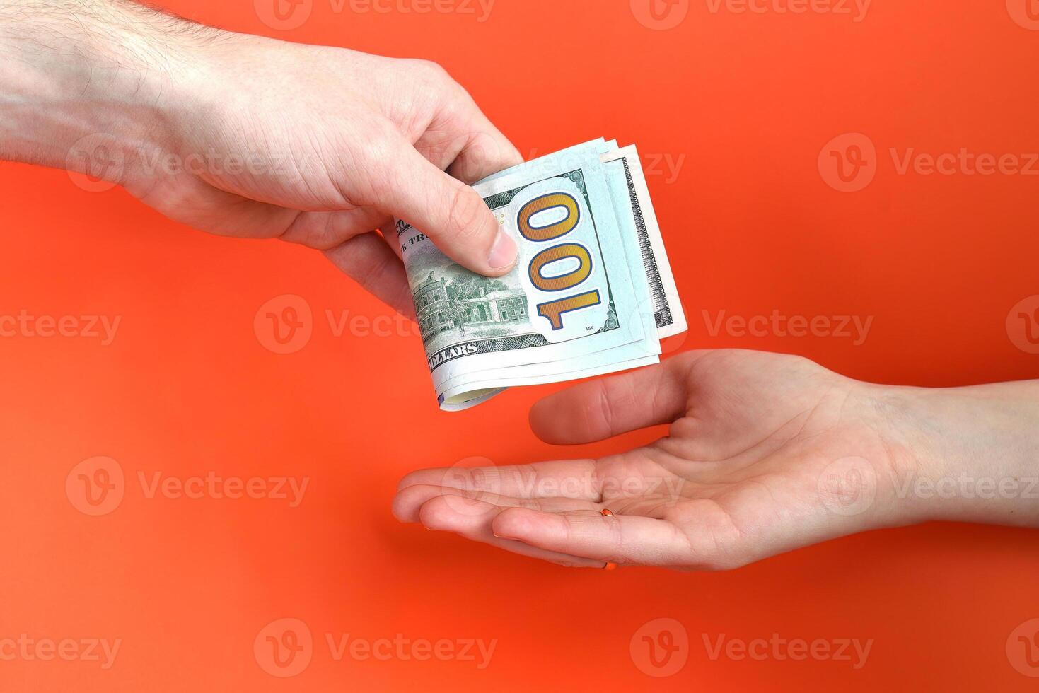 Hand giving folded money usa dollar in other hand on a red background. Bribe concept. photo