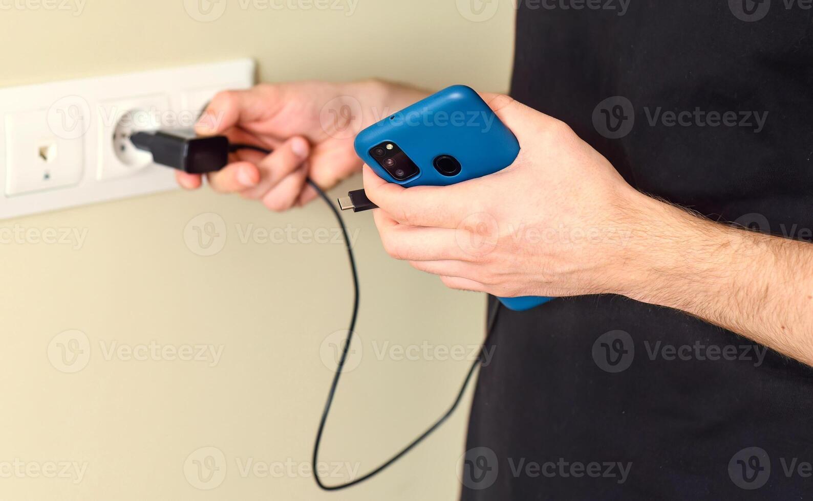Hands inserting smarthone charger into a socket photo