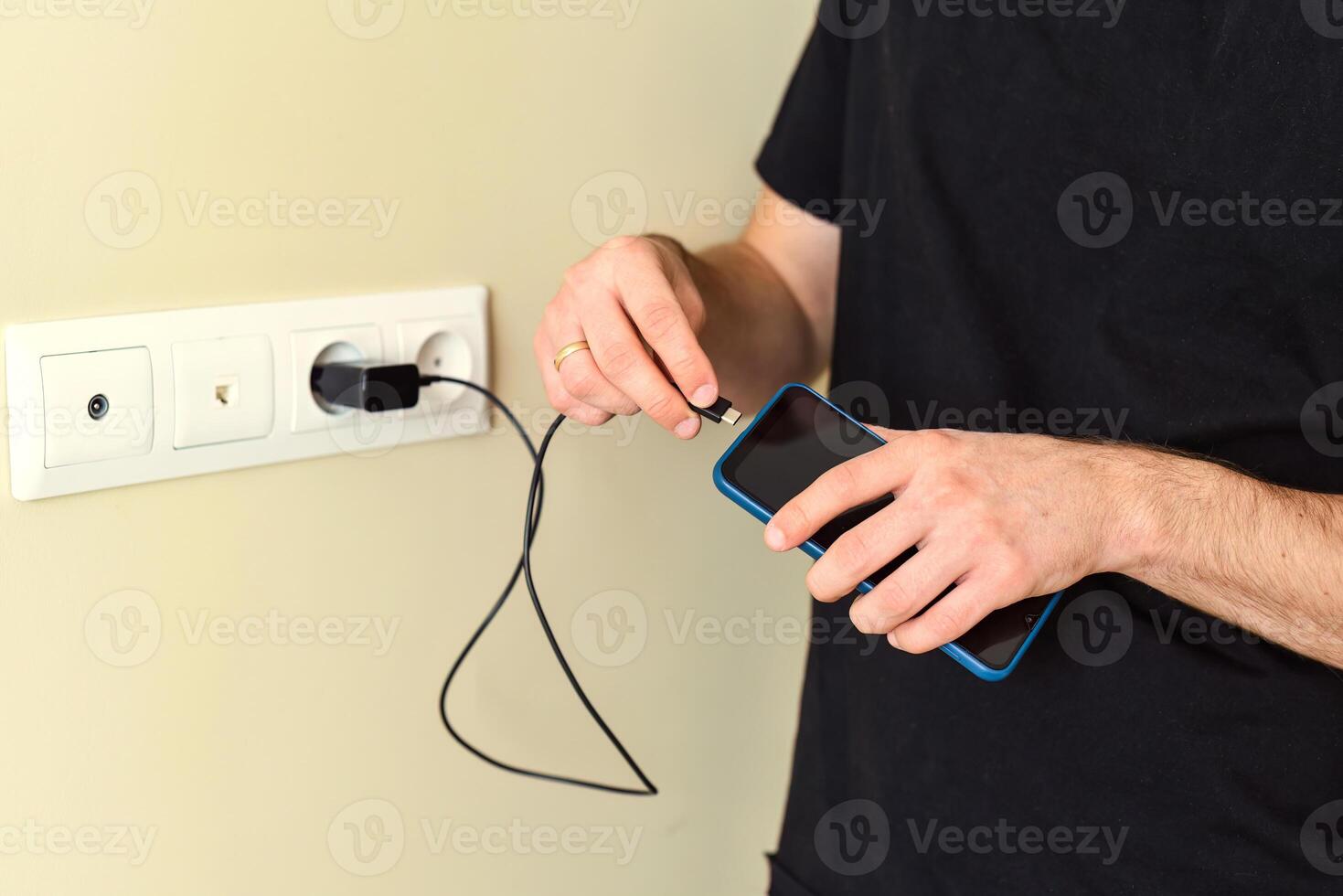 Hand inserting smarthone charger into a socket photo