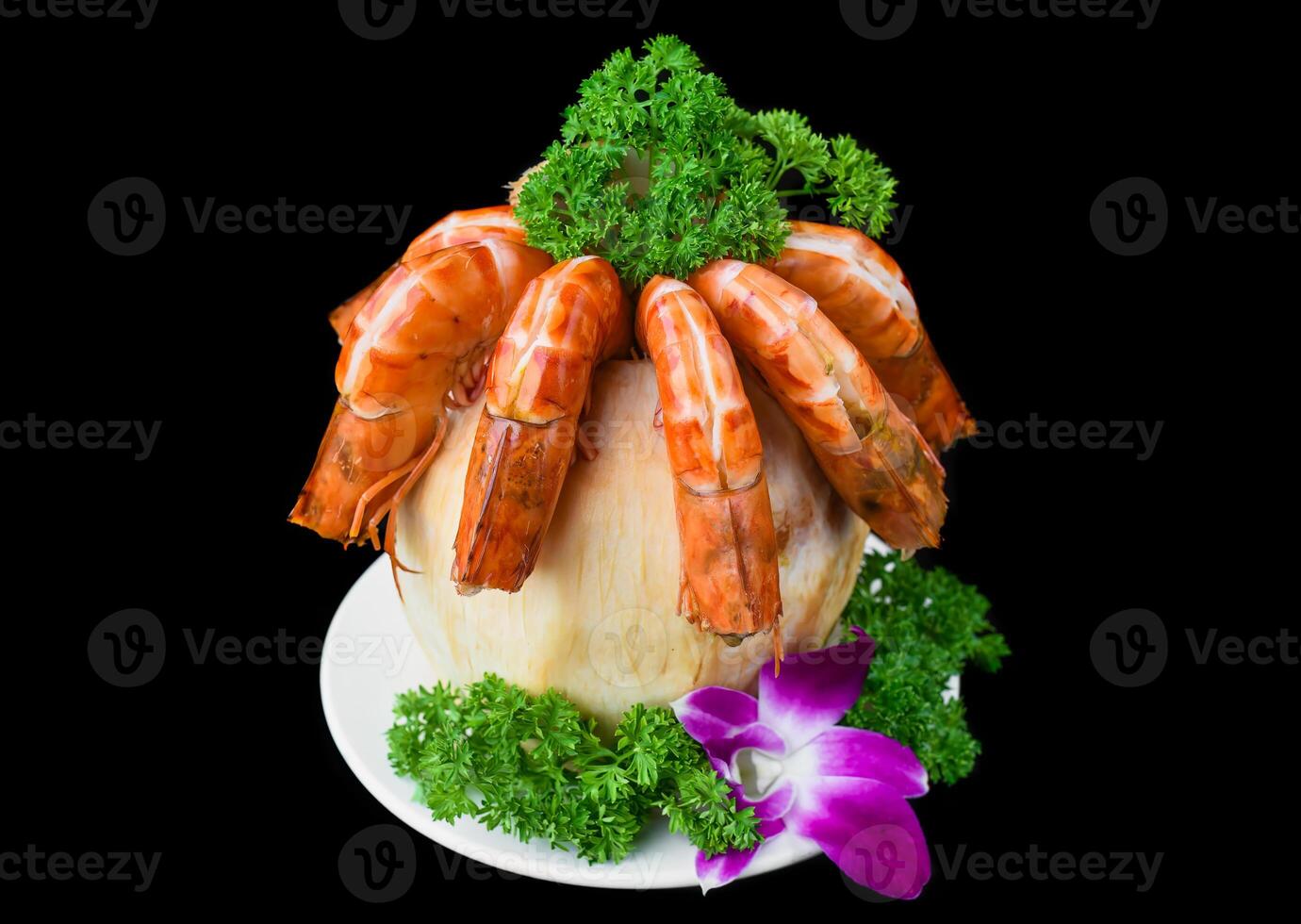 Orange shrimps inside of coconut with sauce isolated on black background side view photo