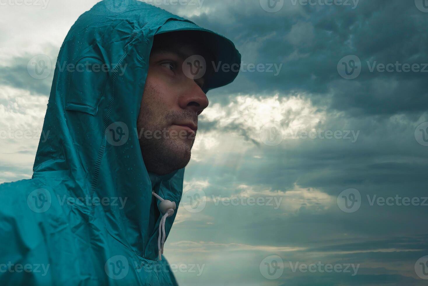 Depressive concept with lonely man in raincoat standing on wet road under rain close up photo