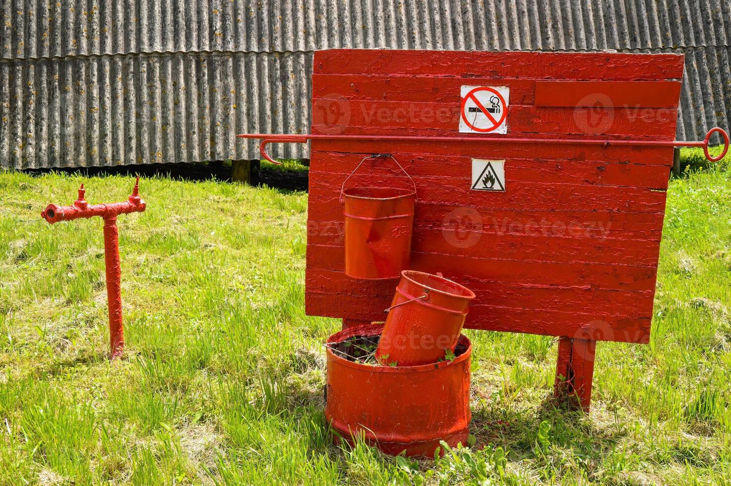 Fire extinguishing equipment. two buckets and shovel hanging on the board. Shabby and old with rusty red paint photo