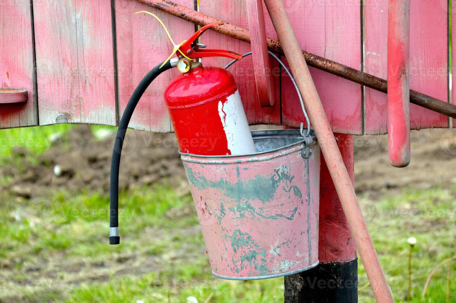 Fire extinguisher in a bucket hanging on a red board photo