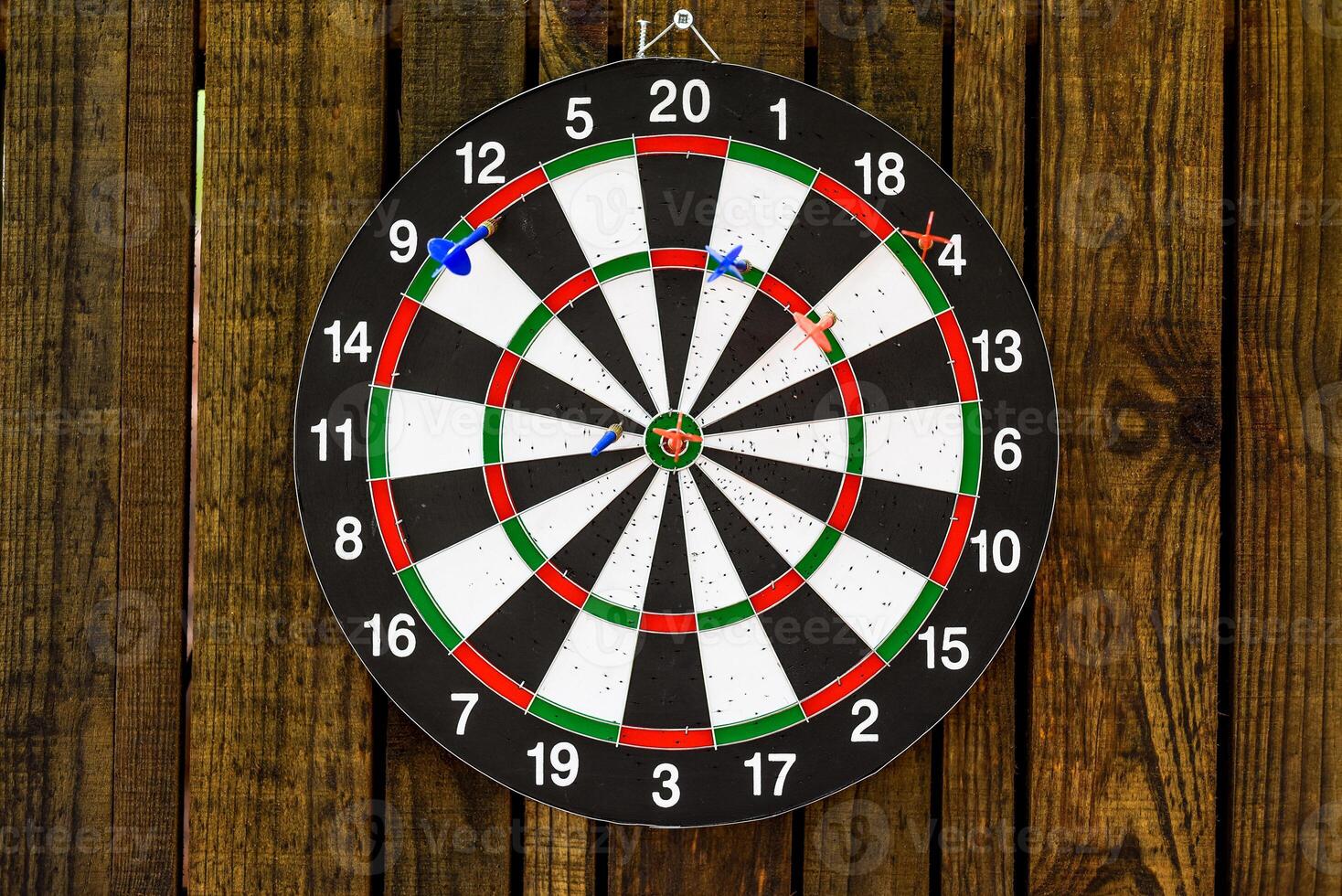 darts hanging on a wooden wall with a dart stuck in the center photo