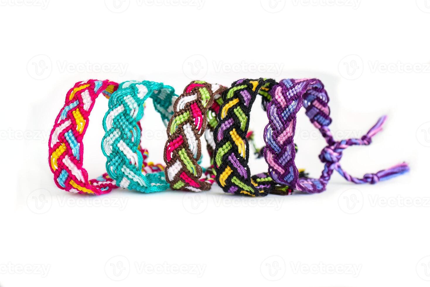 5 Multicolored woven DIY friendship bracelets handmade of embroidery bright thread with knots isolated on white background photo