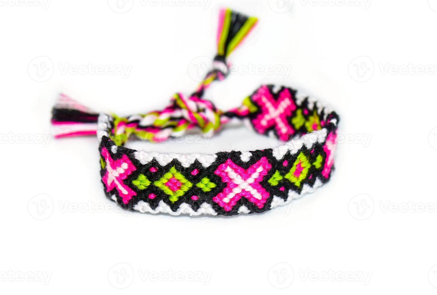 Multicolored pink DIY friendship bracelet handmade of embroidery bright thread with knots isolated on white background photo