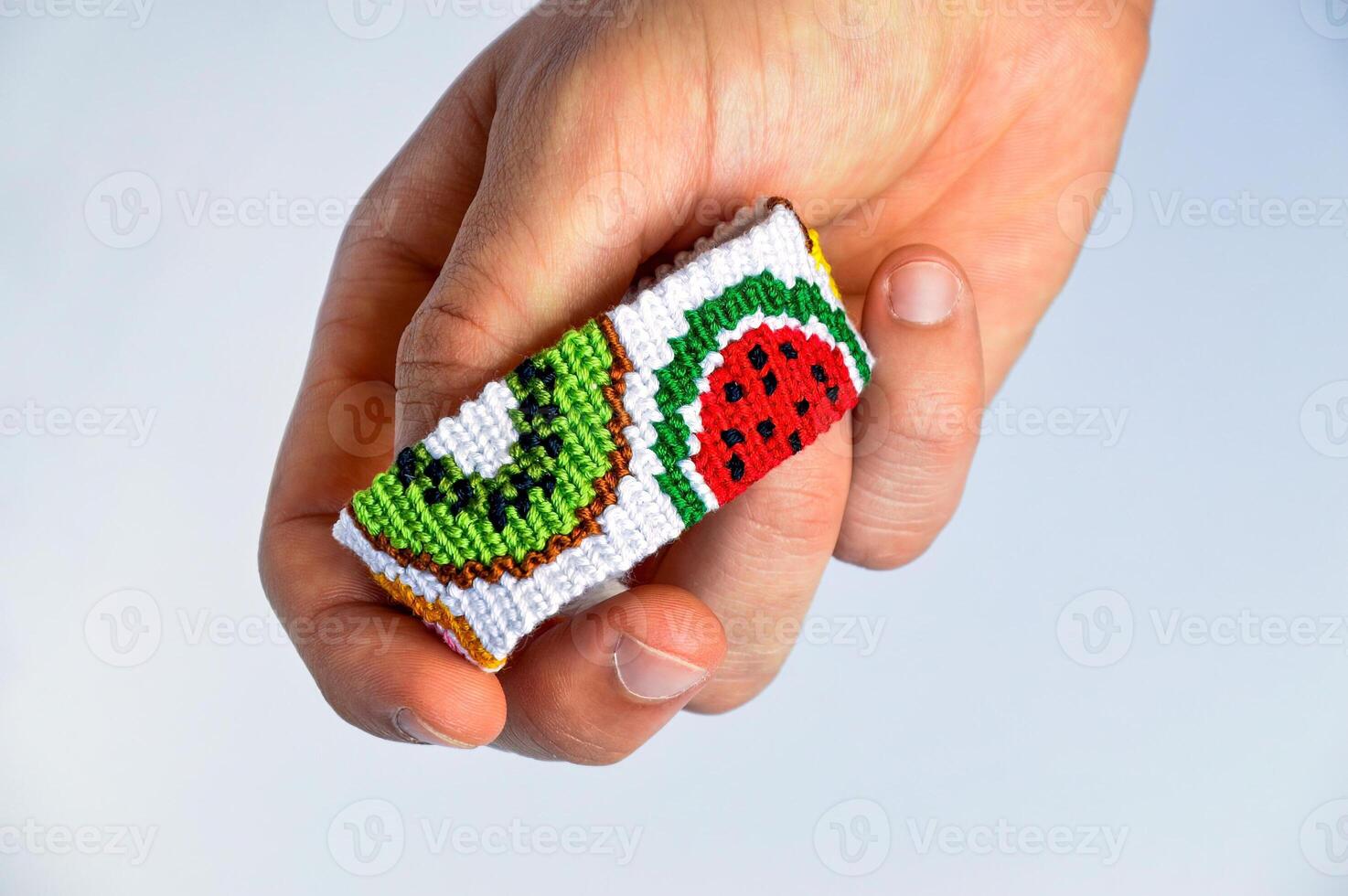 Male hand with woven friendship bracelet handmade of thread with fruit pattern isolated on white background photo