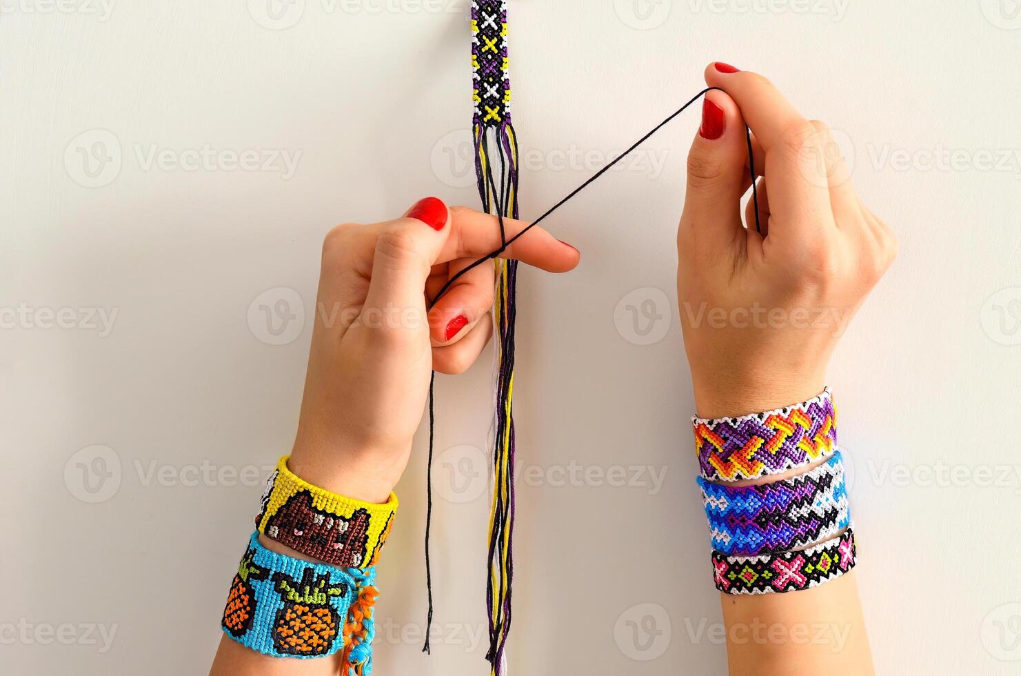 Process of weaving knot for DIY friendship bracelet. Female hands with many handmade bracelets on wrists. step by step. photo