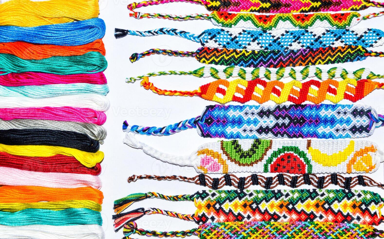 Woven handmade friendship bracelets with bright colorful pattern with thread on white background photo