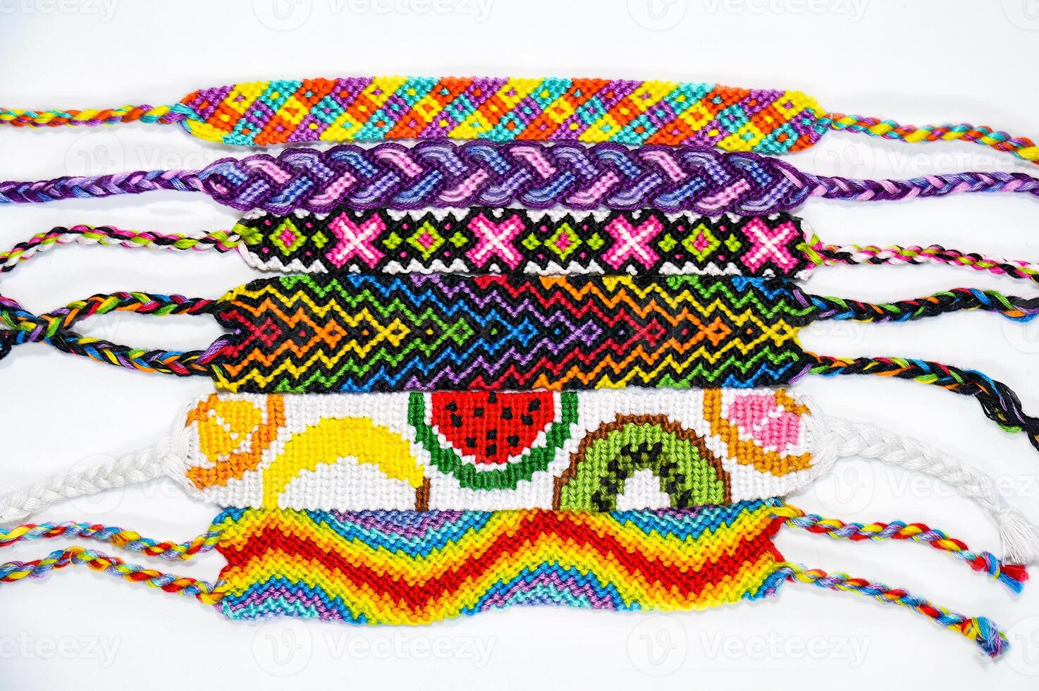 many multicolored woven DIY friendship bracelets handmade of embroidery bright thread with knots isolated on white background photo