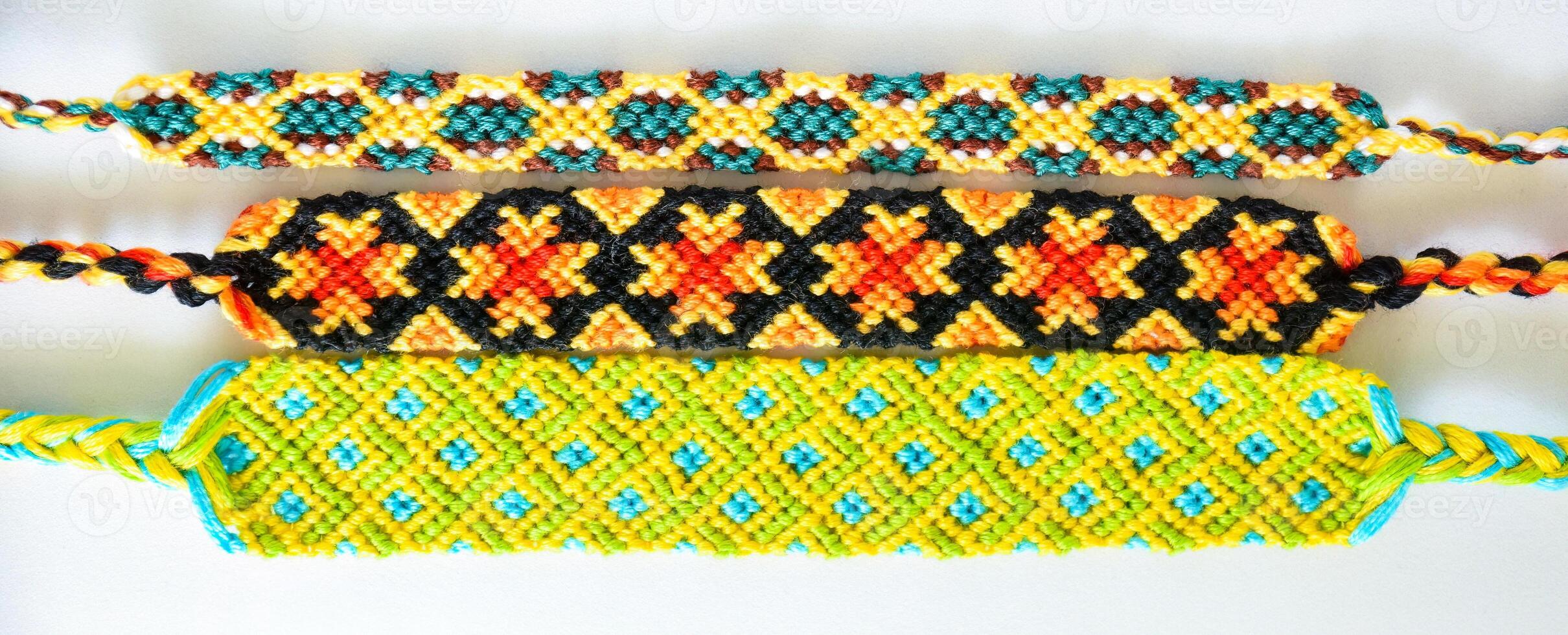 Multicolored woven DIY friendship bracelets boho handmade of embroidery bright thread with knots isolated on white background photo