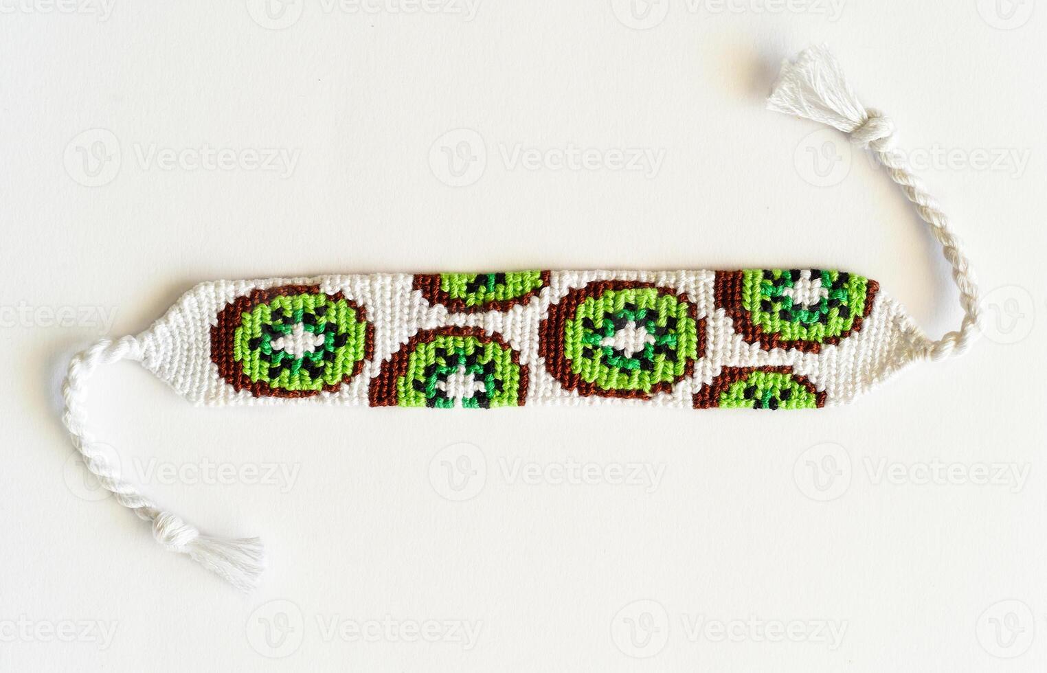 Woven DIY friendship bracelet handmade of embroidery floss with alpha kiwi pattern photo