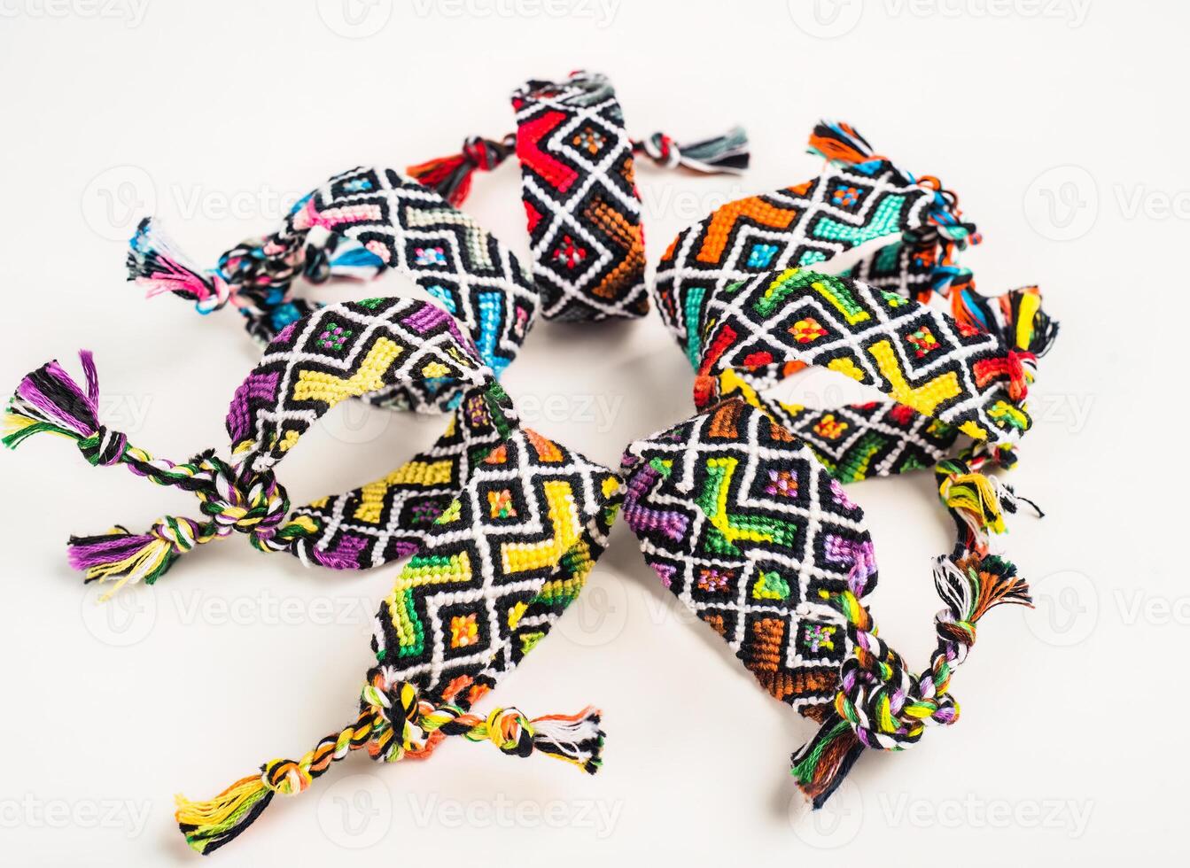 Multicolored woven DIY friendship bracelets handmade of embroidery bright thread with knots isolated on white photo
